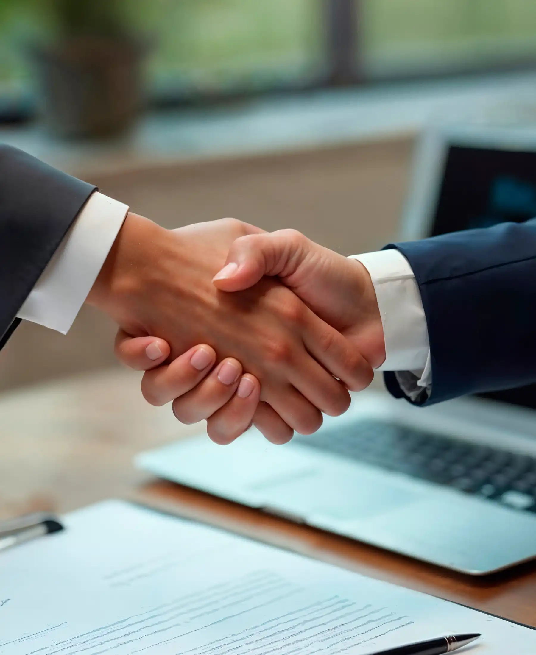 Two business professionals shaking hands over a table during a meeting