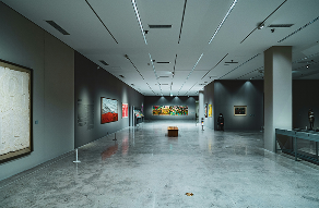 Spacious modern art gallery exhibition with polished concrete floors and contemporary art pieces on display